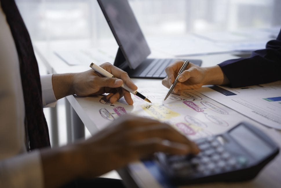 Business partners working together on a new project using a flowchart and a calculator